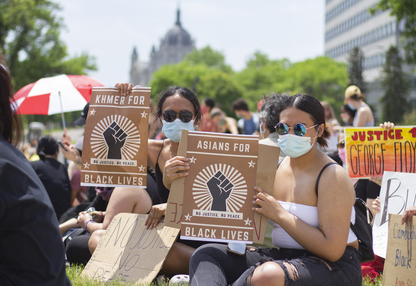 Two people with masks at a demonstration holding signs that read "Asians for Black Lives"