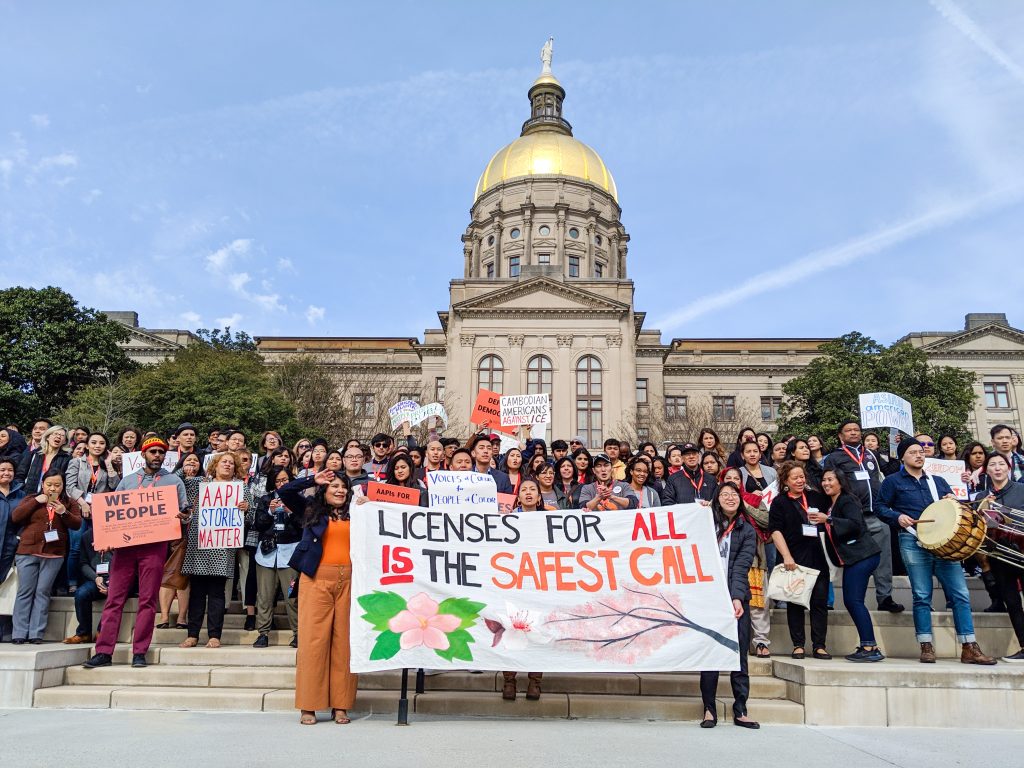 A rally in front of the Georgia State Capitol. A big sign in the front of the group that reads, "Licenses for all is the safest call."